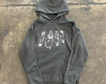 May include: A charcoal gray hoodie with a drawstring hood and a kangaroo pocket. The front features a white graphic of stylized figures. The hoodie is made of a soft, comfortable material.