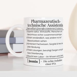 Könnte beinhalten: Weiße Keramik-Tasse mit dem deutschen Text "Pharmazeutisch-technische Assistentin" und einer Definition. Die Tasse hat einen gebogenen Henkel und steht vor einem neutralen Hintergrund mit Büchern und einer Vase.