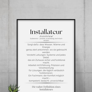 Könnte beinhalten: Ein gerahmter Druck mit dem Wort "Installateur" in großer, fetter Schrift. Der Druck enthält eine Definition auf Deutsch, die die Rolle eines Installateurs beschreibt. Eine kleine Topfpflanze steht unter dem Rahmen.