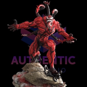 Puede incluir: Estatua roja y negra de Carnage en pose amenazante, sobre una base rocosa. La figura tiene garras afiladas, una larga lengua y múltiples zarcillos. La palabra "AUTHENTIC" es visible.
