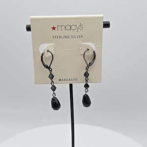 May include: Black sterling silver dangle earrings with faceted beads and teardrop-shaped pendants. The earrings are displayed on a Macy's branded tag that reads "STERLING SILVER" and "MARCASITE".