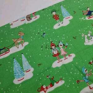 May include: Green fabric with a repeating pattern of elves, deer, and Christmas trees. The elves are wearing red and white clothing and are singing carols. The deer is brown and has antlers. The Christmas trees are green and have blue and white decorations.