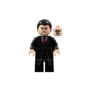 Può includere: Una minifigure Lego di un uomo in abito nero con cravatta rossa. La figura ha un'espressione seria e una testa separata con occhiali. Un giocattolo da collezione.