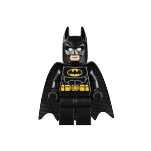 Op de afbeelding: Een zwarte Lego Batman minifiguur met een zwarte cape. De figuur heeft een geel en zwart vleermuissymbool op de borst en een gele gereedschapsriem. Het hoofd heeft een zwarte kap met witte ogen en een neutrale uitdrukking.