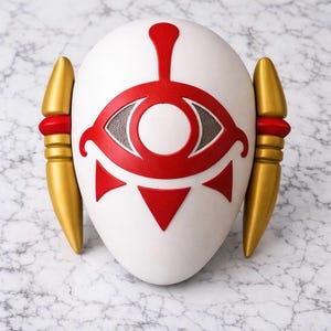 May include: White mask with a red eye design, red accents, and gold side pieces. The mask has a symmetrical design with a central eye symbol and is likely a costume or decorative item.