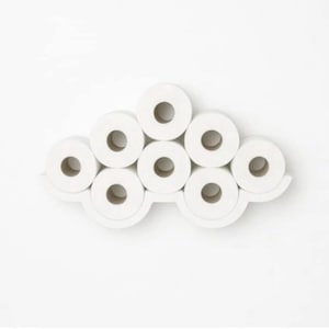 May include: A white, cloud-shaped toilet paper holder with eight rolls of white toilet paper. The holder is mounted on a white wall. The rolls are arranged in a decorative pattern, creating a functional and stylish bathroom accessory.