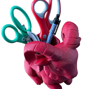 May include: A white ceramic mug with a black handle and the text "But First, Coffee" in a bold, black font. The mug is set against a blurred background, suggesting a cosy setting.