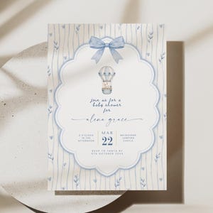 Puede incluir: Una tarjeta de invitaci&oacute;n rectangular para baby shower con un lazo azul claro en acuarela en la parte superior y una ilustraci&oacute;n de globo aerost&aacute;tico. El texto dice: Join us for a baby shower for alena grace, MAR 22, 3 O'CLOCK IN THE AFTERNOON, MELBOURNE JUMPING CASTLE, RSVP TO TANYA BY 5TH OCTOBER 20XX.