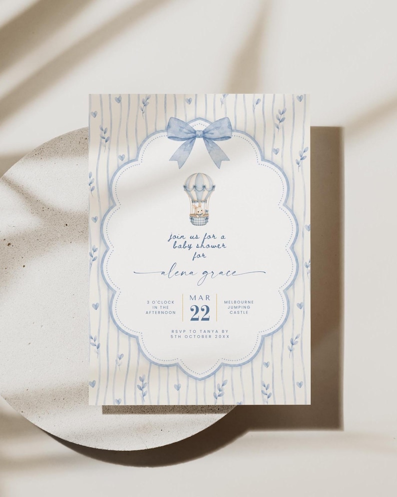 Puede incluir: Una tarjeta de invitaci&oacute;n rectangular para baby shower con un lazo azul claro en acuarela en la parte superior y una ilustraci&oacute;n de globo aerost&aacute;tico. El texto dice: Join us for a baby shower for alena grace, MAR 22, 3 O'CLOCK IN THE AFTERNOON, MELBOURNE JUMPING CASTLE, RSVP TO TANYA BY 5TH OCTOBER 20XX.