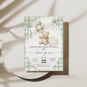 May include: A rectangular invitation card with a green and white gingham border. The center features a watercolor illustration of a brown teddy bear holding a bunch of balloons, a cloud, and two green ribbons. Text reads: JOIN US FOR A BEARY BIRTHDAY FOR alena grace MAR 22 3 O'CLOCK IN THE AFTERNOON MELBOURNE JUMPING CASTLE RSVP TO TANYA BY 5TH OCTOBER 20XX.