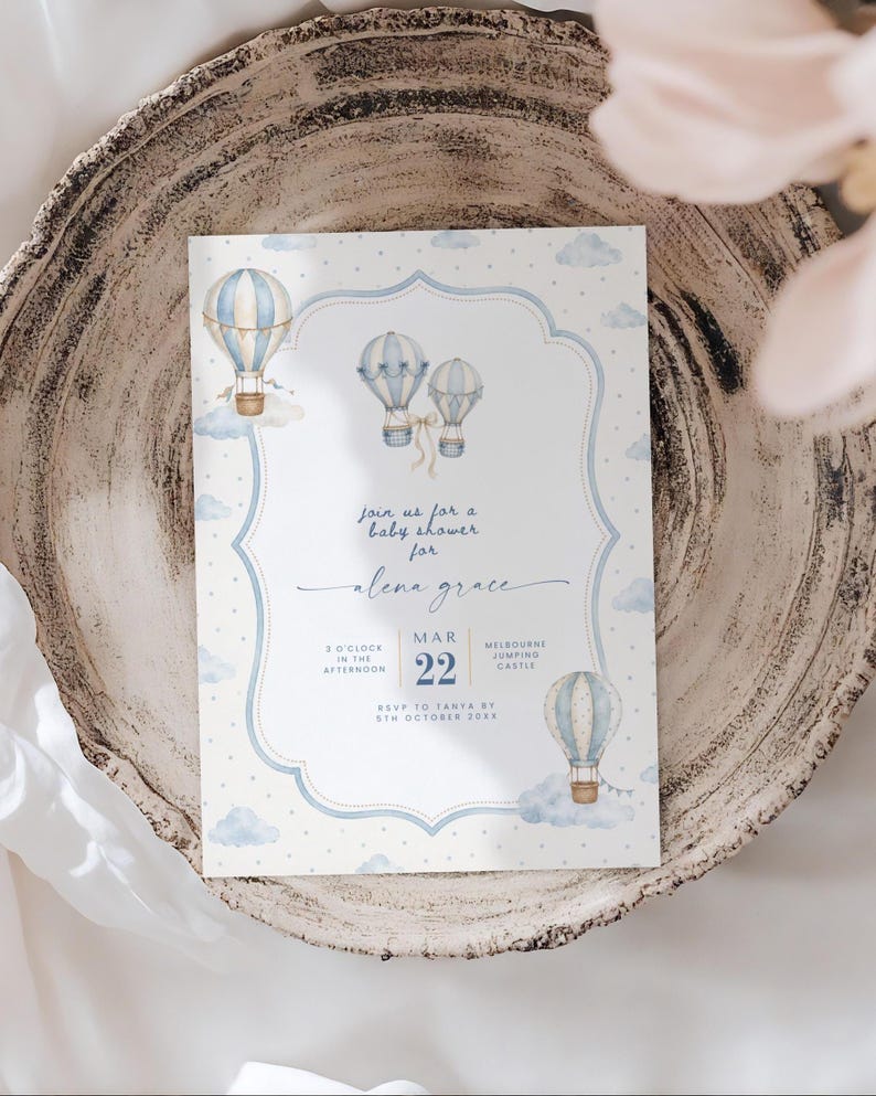 Puede incluir: Una tarjeta de invitaci&oacute;n rectangular para baby shower con ilustraciones en acuarela de globos aerost&aacute;ticos de color azul claro y blanco y nubes sobre un fondo blanco con lunares. El texto dice: Join us for a baby shower for Alena Grace, Mar 22.