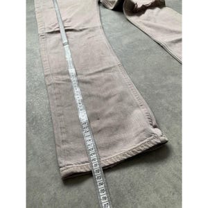 May include: Light brown denim pants with a straight leg design. A measuring tape is laid along the length of the pants. The pants are made of a sturdy material and appear to be in good condition.
