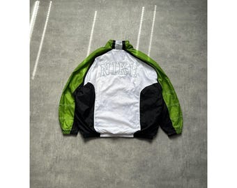 May include: A vintage Nike windbreaker jacket in green, black, and white. The jacket features the Nike logo across the back in a stitched design. The jacket has a full zipper and a high collar.