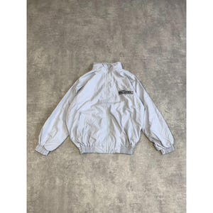 Può includere: Giacca blu chiaro con zip e piccolo logo sul petto. La giacca ha un collo alto, polsini elasticizzati e orlo a coste. La giacca è realizzata in materiale leggero ed è adatta per essere indossata a strati.
