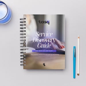 May include: A spiral-bound notebook titled "Service Discovery Guide" with the text "250+ Ways VAS Add Value." A blue pen, a white pencil, and a blue-rimmed glass of water are also on the white surface.