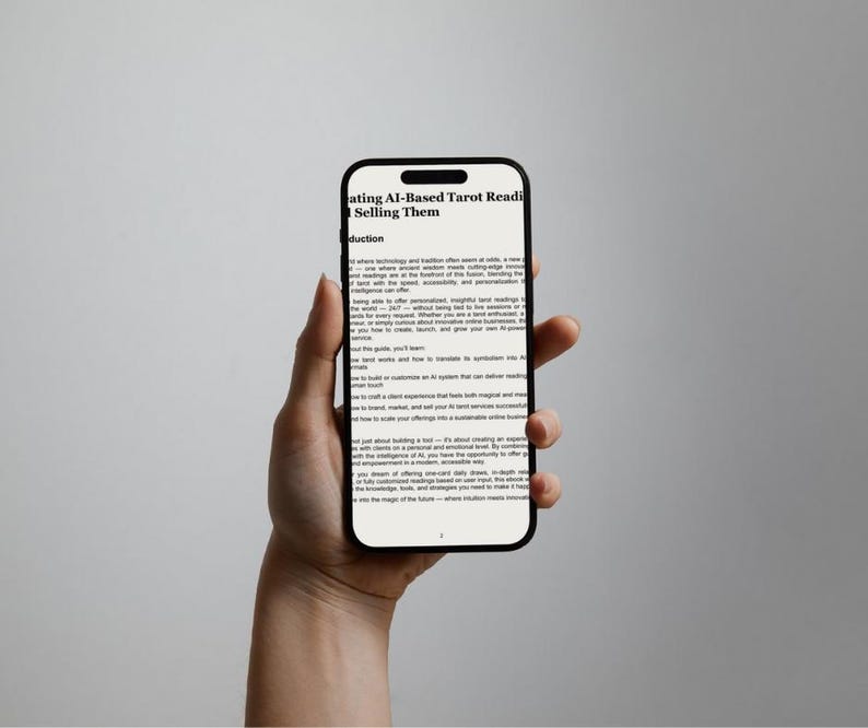 May include: A black smartphone displays text: "ating AI-Based Tarot Readings & Selling Them." The phone is held in a hand against a neutral background. The screen shows multiple lines of text, suggesting an e-book or article.