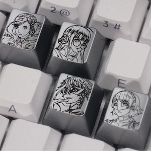 May include: Close-up of a computer keyboard with custom keycaps. The keycaps feature black and white line art illustrations of anime characters. The keys are a mix of white and gray, with some keys showing numbers and letters.