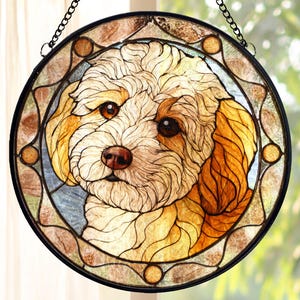 May include: Round stained glass window featuring a detailed portrait of a dog. The dog has light brown and white fur, with brown eyes and nose. The window is framed in black and has a decorative border with brown and tan accents, and is suspended by a chain.