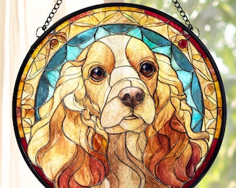 May include: A round stained glass window featuring a dog's face. The dog has brown eyes, a pink nose, and long, flowing, light brown fur. The window is framed in black and has a chain for hanging. The background features a mix of blue, yellow, and red glass.