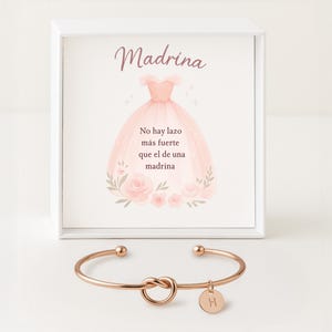Peut inclure: Un bracelet en or rose avec un design de nœud et un petit charme circulaire avec la lettre "H". Le bracelet est présenté devant une boîte blanche avec une illustration rose d'une robe et du texte en espagnol.
