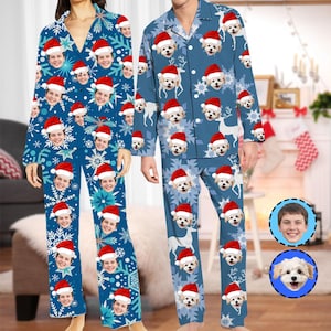 May include: Matching blue Christmas pyjamas with a custom face print and snowflake design. The pyjamas feature a button-down top and trousers. The design includes faces wearing Santa hats and reindeer.