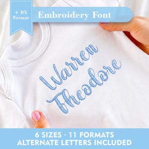 Può includere: Body da bambino bianco con il nome "Warren Theodore" ricamato in corsivo azzurro. L'immagine include il testo "Embroidery Font", "6 Sizes - 11 Formats" e "Alternate Letters Included".