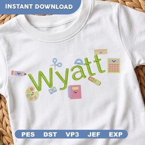 May include: A white t-shirt featuring the embroidered name Wyatt in bright green letters, surrounded by colorful school supply icons including a pencil, scissors, protractor, ruler, paint palette, notebook, highlighter, and a calculator.