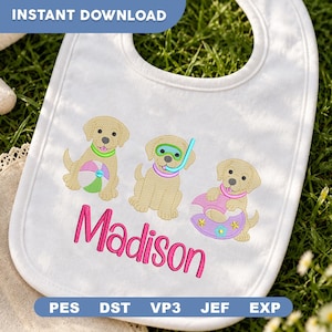 May include: A white baby bib featuring an embroidered design of three golden puppies. One puppy holds a beach ball, one wears a snorkel and mask, and one sits in a pool float. The name Madison is embroidered below in bright pink script lettering.