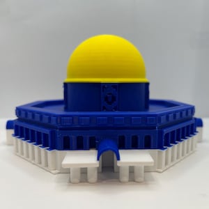 May include: A 3D-printed model of the Dome of the Rock. The model features a yellow dome atop a blue structure with white accents. The architectural model is a detailed representation of the iconic landmark.