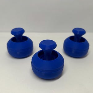 May include: Three blue, spherical objects with a rounded top and a stem-like handle. The objects are arranged on a white surface, with the central one in focus. The design is simple and modern, with a smooth, matte finish.