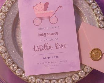 Peut inclure: Une invitation rose pour une baby shower avec une illustration de landau, le texte "Rejoignez-nous pour une baby shower en l'honneur d'Estella Rose" et la date 01.06.2023. Une enveloppe avec un sceau doré est également présente.