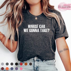 Può includere: T-shirt grigio scuro con la scritta bianca "WHOSE CAR WE GONNA TAKE?" in caratteri usurati. La maglietta è una Bella Canvas 3001, colore grigio scuro mélange. Girocollo.