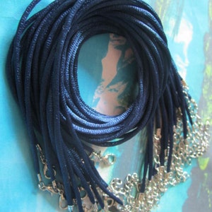 May include: A bulk pack of navy blue cord with silver lobster clasps. The cord is wound into a coil and the clasps are arranged in a row.