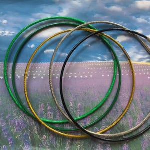 May include: Five different coloured cable chains, including green, gold, silver, and black, are arranged in a circle on a purple and white background.