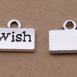 May include: Two silver charm pendants, one with the word "wish" in black lettering and the other blank.