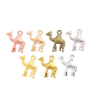 Op de afbeelding: Assortiment van zes kameelcharms in verschillende metaalafwerkingen: goud, zilver, brons en rosé goud. De charms zijn gedetailleerd met textuurhaar en hebben een lus om aan sieraden of knutselwerk te bevestigen.