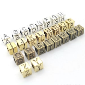 Può includere: Assortimento di perline a forma di cubo in metallo, ognuna incisa con una lettera diversa dell'alfabeto. Le perline sono disponibili in varie finiture metalliche, tra cui argento, oro e bronzo. Queste perline alfabetiche sono ideali per la creazione di gioielli e progetti di artigianato.