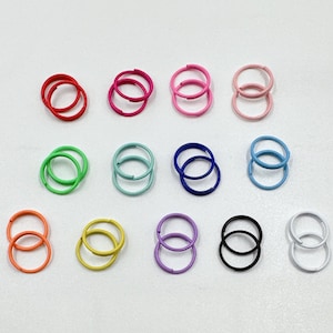 May include: Assortment of 12 pairs of hoop earrings in various colors, including pink, blue, green, yellow, and white. The earrings are all double-hooped and are arranged in two rows.