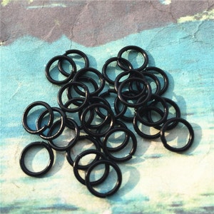 May include: A pile of black metal jump rings. The rings are small and round, and they are perfect for jewelry making or other crafts.