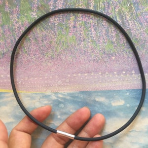 Puede incluir: Un collar de goma negro con un cierre plateado.