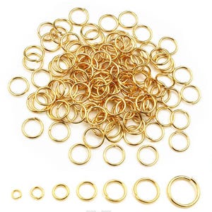 Peut inclure: Un assortiment de anneaux de jonction dorés de différentes tailles, disposés sur une surface blanche. Les anneaux sont en métal et semblent neufs. L'image présente une variété de tailles, petites et grandes, pour la fabrication de bijoux ou l'artisanat.