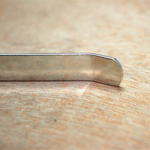 May include: Close-up of a silver metal tire tool with a rounded edge.