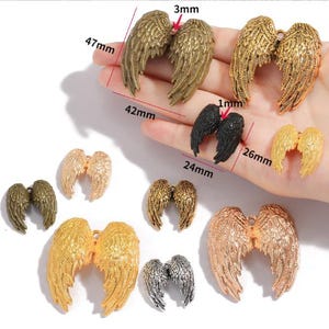 Può includere: Assortimento di ciondoli a forma di ali d'angelo in metallo, in vari colori tra cui oro, argento, bronzo e nero. Le ali più grandi misurano 47 mm di lunghezza. Adatto per la creazione di gioielli e progetti di artigianato.