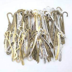 May include: A large collection of metal bookmarks in various finishes including gold, silver, and bronze. The bookmarks feature diverse intricate patterns such as feathers, floral motifs, suns, and geometric designs, each with a curved hook top.