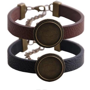 May include: Two leather bracelets, one brown and one black, each featuring a round, antique bronze-colored bezel. The bracelets have a simple design with a metal clasp and adjustable chain.