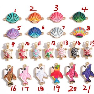 May include: A collection of colorful seashell, turtle, and shark charms. The seashell charms feature various colors, including green, orange, pink, blue, and rainbow. The turtle charms are decorated with floral patterns and the shark charms are painted in various colors.