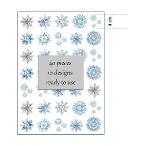 Op de afbeelding: Een vel met 40 sneeuwvlokstickers in 10 ontwerpen, klaar voor gebruik. De sneeuwvlokken zijn in tinten blauw en grijs, met een aquareleffect. Het vel is 4 cm hoog.
