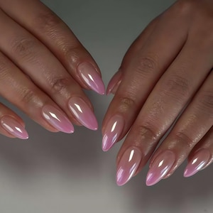 May include: Close-up of hands with long, almond-shaped, pink iridescent nails. The nails have a glossy finish and a subtle color gradient, transitioning from a pale pink at the base to a vibrant pink at the tips. The overall effect is elegant and polished.