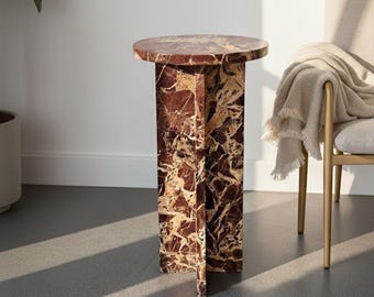 May include: A decorative side table with a round top and a rectangular base. The table is made of marble with a reddish-brown and beige pattern. The table is approximately 24 inches tall.