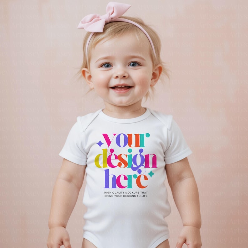 May include: A smiling baby wearing a white onesie with the text "YOUR design here" in colorful letters. The onesie also has the text "HIGH QUALITY MOCKUPS THAT BRING YOUR DESIGNS TO LIFE". The baby is wearing a pink headband with a bow.